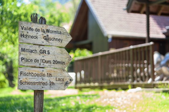 Panneaux de direction en bois près d'une maison en nature.