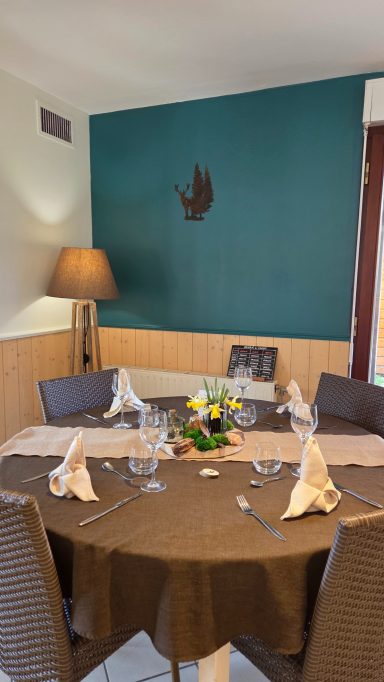 Table dressée élégamment avec serviettes, fleurs et lampe dans une ambiance chaleureuse.