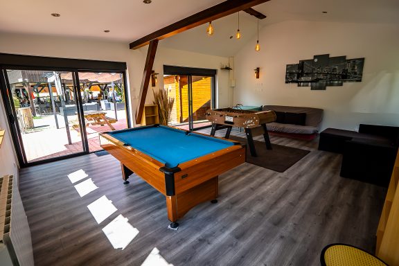 Salle de jeux lumineuse avec tables de billard et de ping-pong, décor moderne.