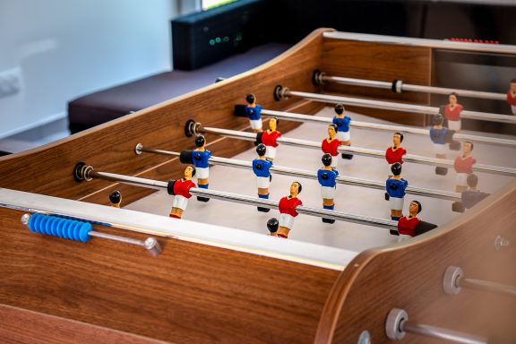 Table de baby-foot avec des figurines rouges et bleues disposées sur le terrain.