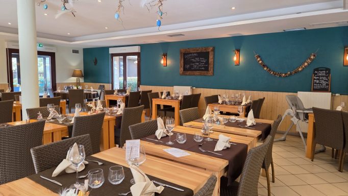 Salle de restaurant avec tables dressées et décoration murale moderne.