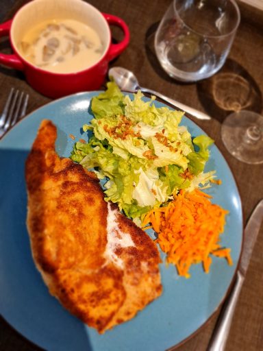 Plat de poulet frit accompagné de salade, carottes râpées et soupe crémeuse.