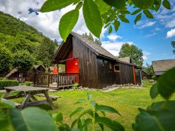 Chalets de la Wormsa et son restaurant Chalet en bois sombre avec une terrasse, entourée de verdure et de montagnes.