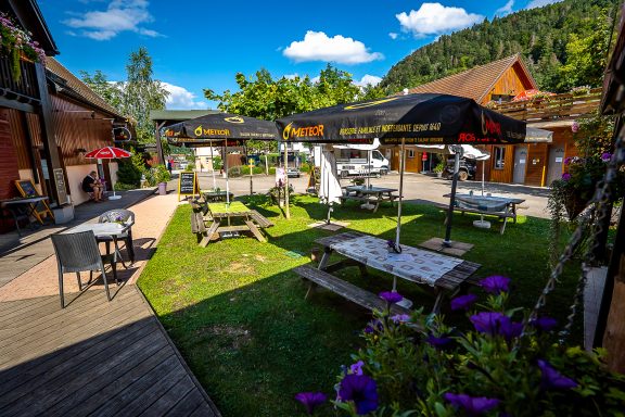 Terrasse du restaurant en plein air avec tables, parasols et verdure.
