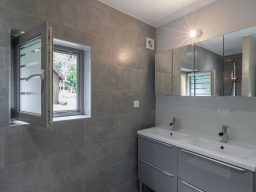 Chalets de la Wormsa et son restaurant Salle de bain moderne avec murs en carrelage gris et double lavabo sous une fenêtre.